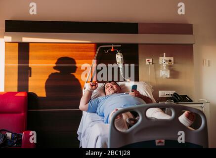 Patient liegt im Krankenhausbett mit Silhouette einer Frau hinter einem Vorhang Stockfoto