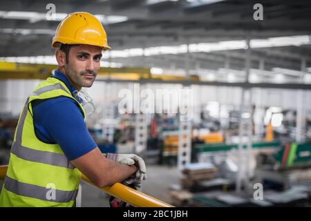 Portrait selbstbewusster männlicher Vorgesetzter, der sich werkseitig auf das Bahnsteiggeländer neigt Stockfoto