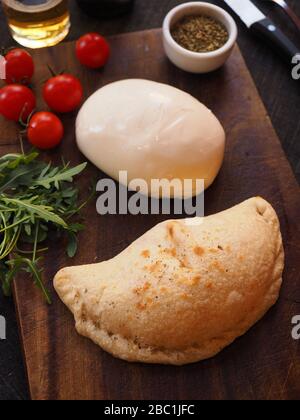 Calzone Pizza mit Raketensalat, kleinen Tomaten, Oregano und Burrata Käse, Italien Stockfoto