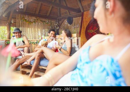 Junge Paare hängen aus und trinken Cocktails im Sommer am Pool Stockfoto