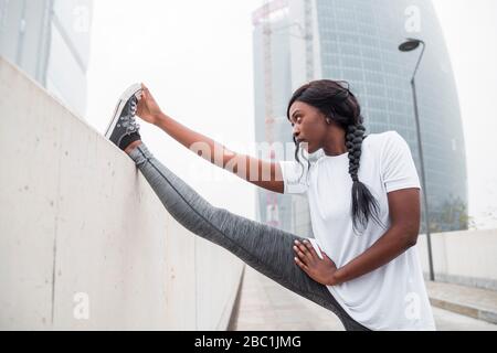 Sportliche junge Frau Stretching in der Stadt Stockfoto