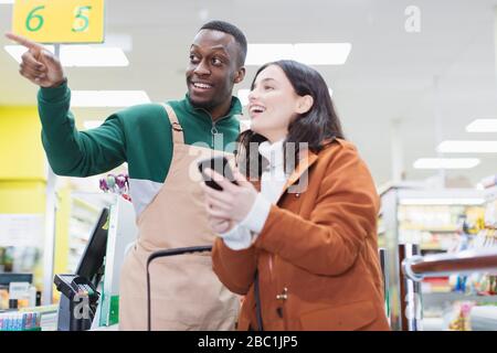 Männlicher Lebensmittelhändler hilft Kunden im Supermarkt Stockfoto