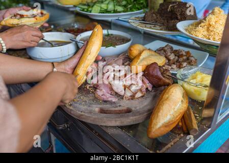 Leute, die Banh Mi, vietnamesisch berühmtes lokales Schweinesandwich, machen Stockfoto