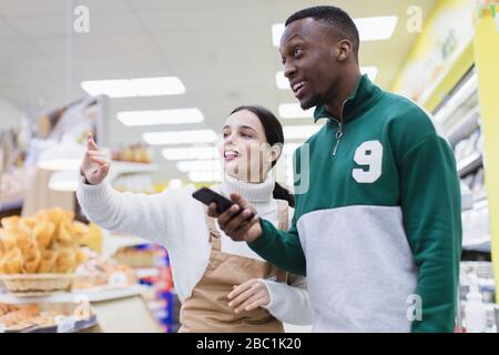 Lebensmittelhändler für Frauen, die Kunden im Supermarkt unterstützen Stockfoto