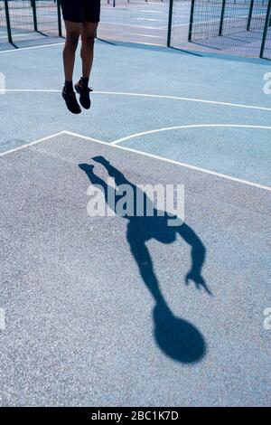 Schatten eines Mannes, der Basketball auf dem Basketballplatz spielt, und dabei dunking Stockfoto