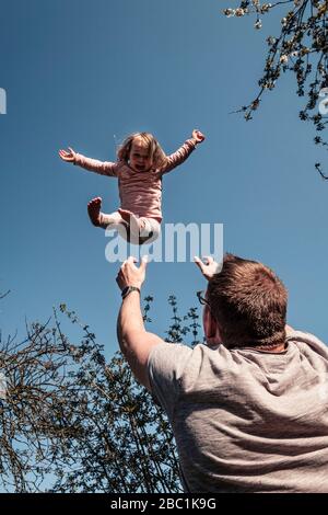 Vater wirft kleine Tochter in die Luft Stockfoto