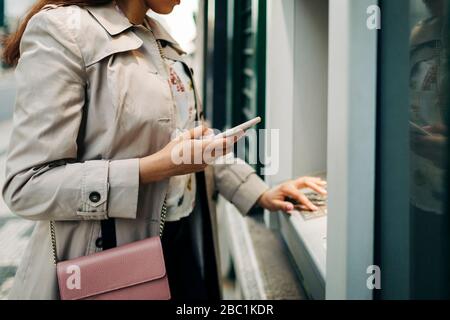 Frau mit geldautomat und Handy Stockfoto