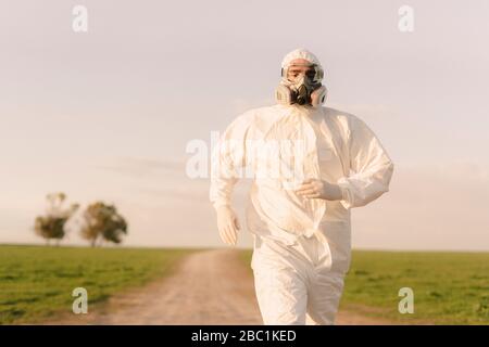 Mann mit Schutzanzug und Maske läuft auf dem Land Stockfoto