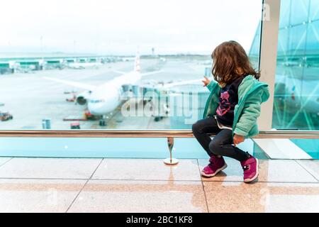 Mädchen sitzt am Flughafen vor einem Flugzeug, bereit zu reisen Stockfoto