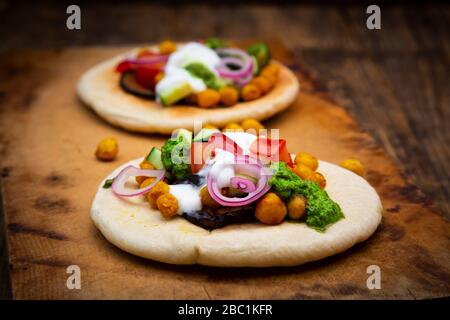 Israelischer Sabich mit Pita-Brot, Auberginen, Kichererbsen, Tomaten, Gurke, Joghurt und Zhoug-Sauce Stockfoto