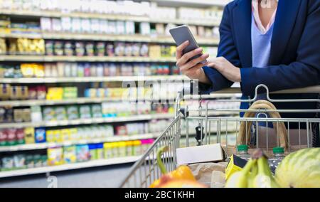 Frau mit Smart-Phone-Shopping im Supermarkt Stockfoto