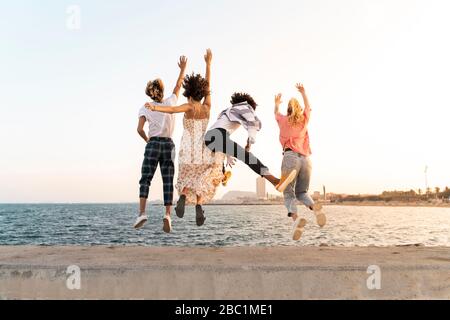 Unbeschwerte Freunde springen auf einer Kaimauer Stockfoto