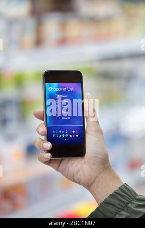 Persönliche Perspektive Frau, die auf dem Smartphone im Supermarkt auf die digitale Einkaufsliste schaut Stockfoto