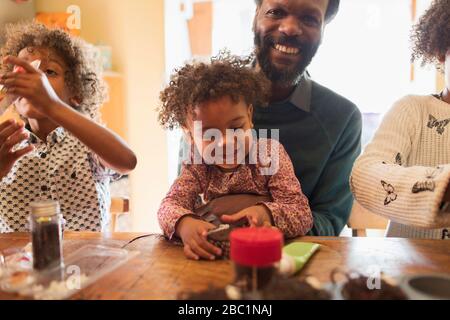 Glücklicher Vater und Kinder schmücken Cupcakes am Tisch Stockfoto