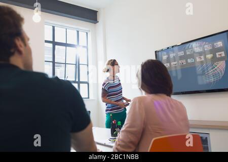 Weibliche Architektin auf Fernsehbildschirm führt Konferenzraum-Meeting Stockfoto