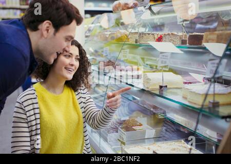 Ein Paar, das Desserts in der Vitrine der Bäckerei betrachtet Stockfoto