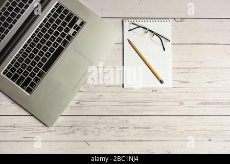 Laptop mit Brille, Notizblock und Bleistift auf leichtem Holztisch, Büromaterial Stockfoto