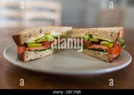 Ein vegetarisches Sandwich mit Avocado und Tomaten auf Vollkornbrot bereit für ein gesundes, leckeres Mittagessen. Stockfoto