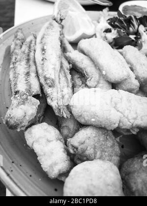 Mischen Sie frittierte Fische und Meeresfrüchte mit frischem Salat und Zitronensaft Stockfoto