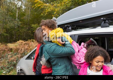 Mutter hält Tochter vor dem Auto auf dem Parkplatz Stockfoto