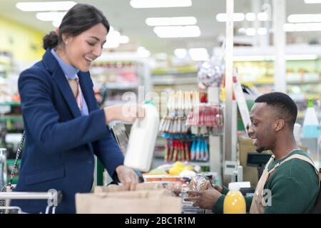 Männliche Kassiererin hilft weiblichen Kunden bei der Kasse im Supermarkt Stockfoto