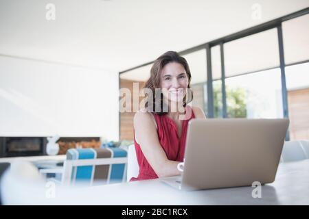 Portrait lächelnde Frau, die in der Küche am Laptop arbeitet Stockfoto