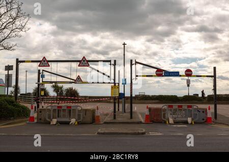 Southend-on-Sea, Großbritannien. April 2020. Betonbarrieren, Verkehrskegel und mehrere Straßenschilder behindern den Zugang zu einem Parkplatz oder einer Straße in Southend-on-Sea. Die Beschilderung enthält Zutrittsverbote und Gefahrenwarnungen, die auf eingeschränkten Zugang aufgrund von Sicherheit oder Wartung hinweisen. Palmen und bewölkter Himmel prägen die urbane Szene. Ein Parkplatz am Meer in Southend wurde mit Betonblöcken abgesperrt, um zu versuchen, die Menschen daran zu hindern, an die Küste zu fahren und soziale Zusammenkünfte während der Coronavirus-Pandemie zu treffen. Penelope Barritt/Alamy Live News Stockfoto