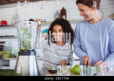 Mutter und Tochter machen in der Küche gesunden grünen Smoothie im Mixer Stockfoto