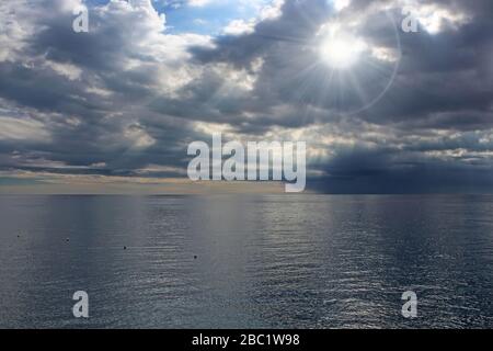 Sonnenstrahlen, die durch die Sturmwolken über das Meer ziehen Stockfoto