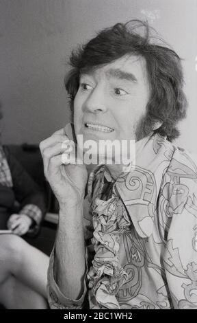 1970er Jahre, britischer Comedian und Entertainer von Kindern, Ken Goodwin, der Make-up vor einer Aufführung anwendet. Typischer 70er-Jahre-Look mit blumiger Hemd und langen Koteletten. Stockfoto