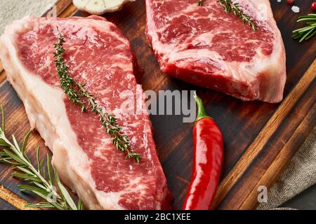 Zwei große ganze Stück rohes Rindfleisch Fleisch, Striploin auf Holz Schneidebrett, Makro, Nahaufnahme Stockfoto