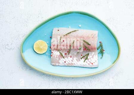 Filet aus rohem weißen Zander-Fisch auf einem blauen Teller auf weißem Hintergrund. Ein ganzes Stück frischen Fisch Stockfoto