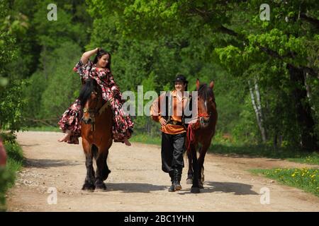 Zigeunerpaar in traditionellen Kostümen spazieren mit einem Pferd im Sommerwald Stockfoto