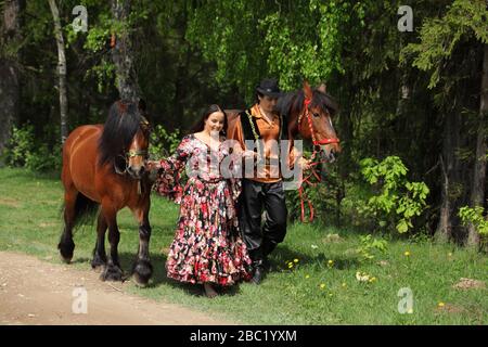 Zigeunerpaar in traditionellen Kostümen spazieren mit einem Pferd im Sommerwald Stockfoto