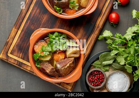 Gulasch mit großen Stücken von Rindfleisch und Gemüse. Burgunderfarbenes Fleisch. Dunkler Hintergrund. Stockfoto