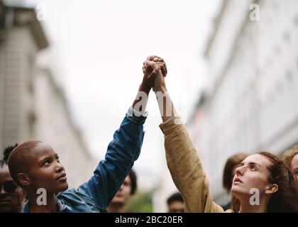 Zwei Frauenaktivisten halten Hände und protestieren. Demonstranten demonstrieren auf der Straße und halten die Hände.