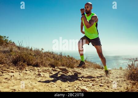 Junger Mann, der auf einem Bergpfad verläuft. Männlicher Läufer arbeitet morgens aus. Stockfoto