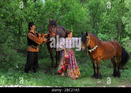 Zigeunerpaar in traditionellen Kostümen spazieren mit einem Pferd im Sommerwald Stockfoto