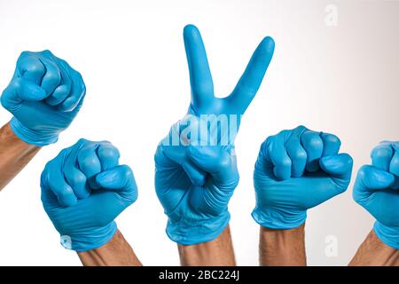 Medizinische Hände mit blauen Handschuhen, eine davon mit V-Geste Stockfoto
