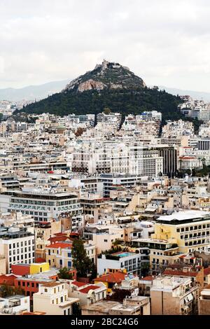 Der Berg Lycabettus erhebt sich über den Gebäuden im Zentrum Athens, Griechenland. Die Kapelle des heiligen Georg führt den Hügel hoch. Stockfoto