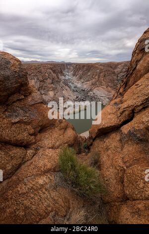 Ein schöner Blick auf die Landschaft der Augrabies Falls Gorge, der Berge und des Flusses in Südafrika, der an einem windigen und stürmischen bewölkten Nachmittag eingenommen wird. Stockfoto