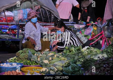 Gemüseverkäufer trägt eine schützende Gesichtsmaske / Abdeckung während der Coronavirus-Pandemie. Der Russische Markt, Phnom Penh, Kambodscha. © Kraig Lieb Stockfoto