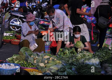 Kambodianischer Gemüseanbieter, der während der Coronavirus-Pandemie eine Maske mit maskierten Kunden trägt. Der Russische Markt Phnom Penh, Kambodscha. © Kraig Lieb Stockfoto