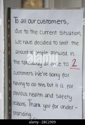 Ein Schild im Fenster eines chinesischen Takeaway in Gillingham North Dorset während des Coronavirus-Ausbruchs, das die Kundenzahlen beim Takeaway auf jeden Fall einschränkt Stockfoto