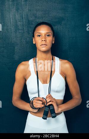 Portrait von fit Young Woman mit einem springenden Seil über schwarzem Hintergrund. Athletin mit Springseil mit Blick auf die Kamera. Stockfoto