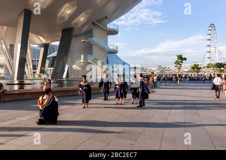 Studenten, die den Abschluss in der Nähe des Lotus Flower Shaped ArtScience Museum in Marina Bay Sands, Singapur feiern Stockfoto