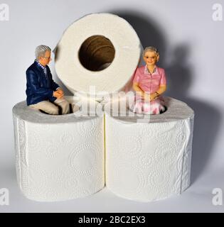 Miniatur-Figurin-Rentner, die vor weißem Hintergrund auf toilettenrollen sitzen Stockfoto