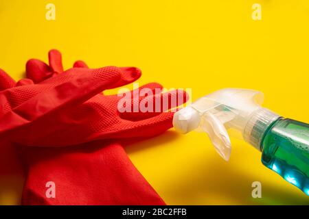 Rote Gummihandschuhe und Flüssigwaschmittel in Sparrenflasche auf gelbem Hintergrund, Reinigungs- und Sanierungskonzept Stockfoto