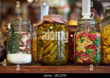 Konserviertes Gemüse in Glasgefäßen auf einem Holzregal eines Schranks. Eingepickte Gurken. Stockfoto