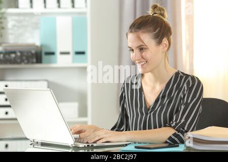 Glückliche Unternehmerin, die einen Laptop auf einem Schreibtisch im Heimbüro verwendet Stockfoto